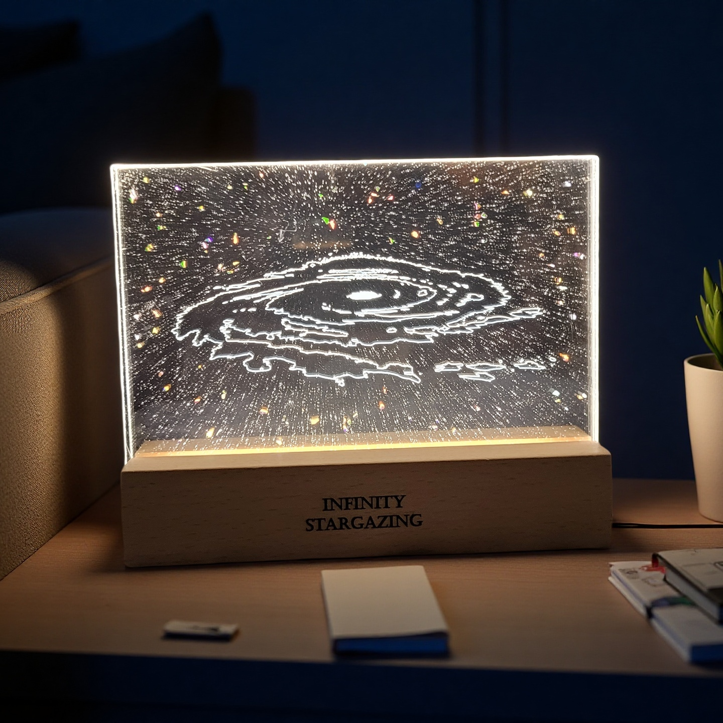 Decorative lamp with starry design on a wooden base, labeled 'Infinity Stargazing', on a desk.